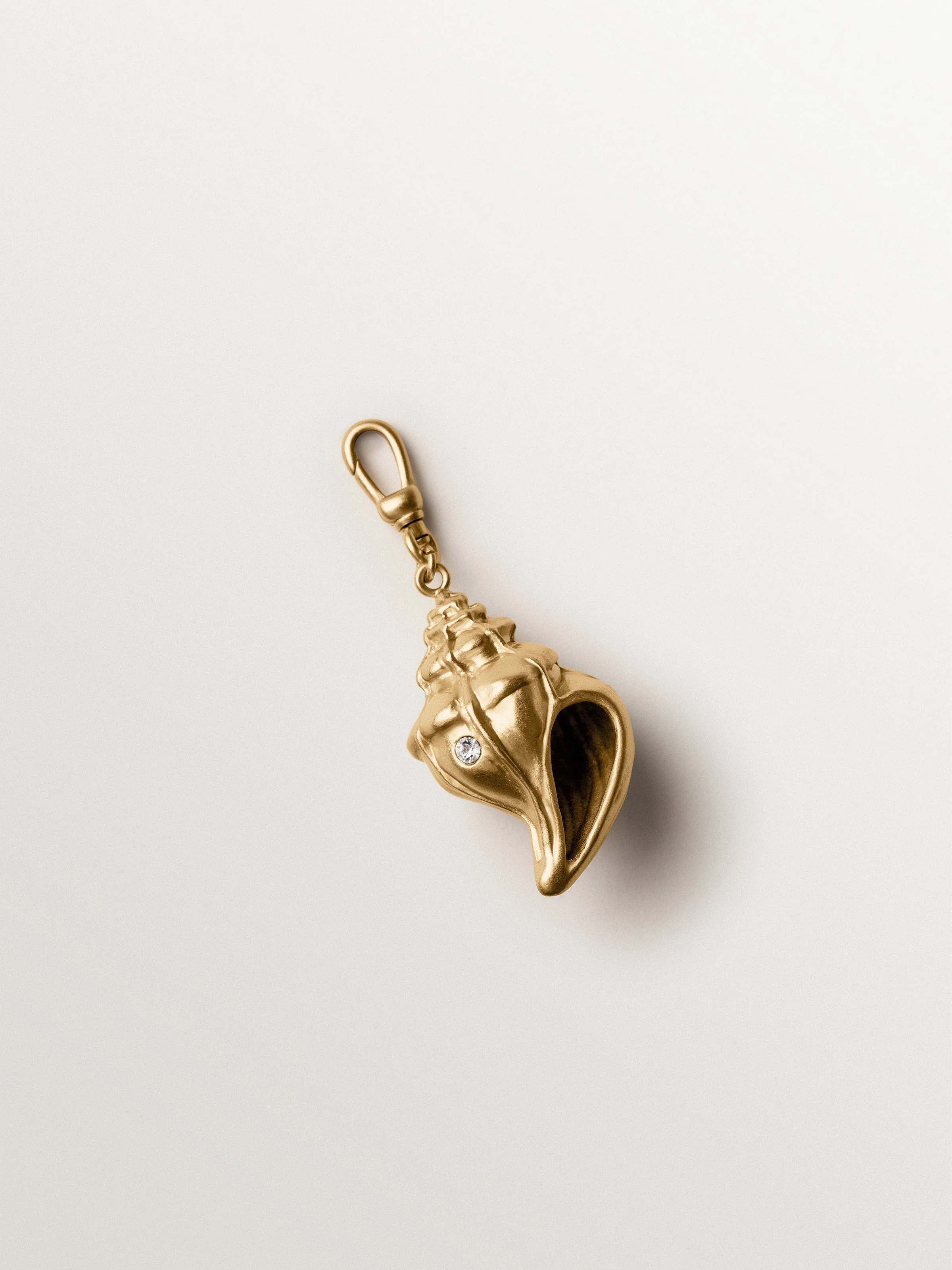 Charm bañado en oro amarillo con cristales y forma de concha